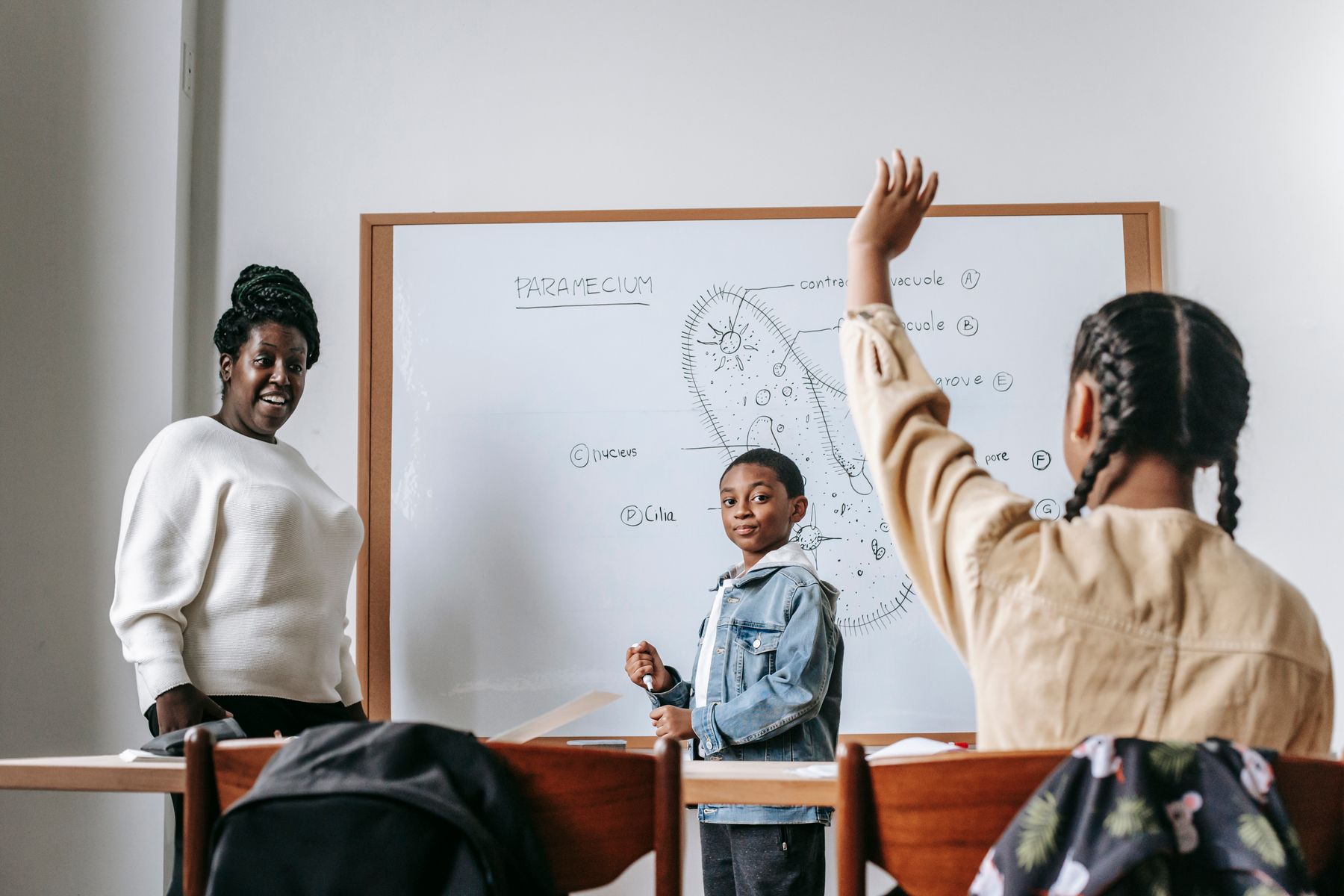 A Black educator and students learning together in a classroom